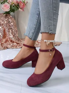 Detail van bordeauxrode suède pumps met een elegante enkelbandsluiting