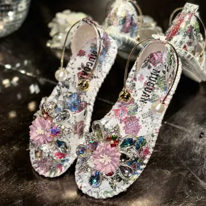 Detailed macro view of floral flat sandals with elegant fabric flower and crystal accents.