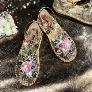 Close-up of floral print flat sandals with crystal flower and pearl decorations