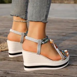 Vue latérale de sandales compensées blanches avec perles colorées et brides argentées.