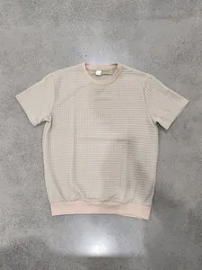 Gedetailleerd overzicht van de wafeltextuur op een casual beige T-shirt met ronde hals.