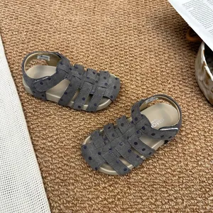 Draufsicht auf graue Mädchen-Römersandalen mit Punkten auf einem Teppich