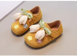 Yellow suede girls' princess shoes with fabric tulip charms and floral embroidery detail.