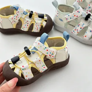 Primer plano de sandalias de verano para niños con lunares de colores y suelas blandas