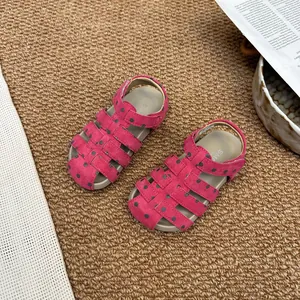 Detailansicht von rosa gepunkteten Mädchensandalen auf einer braunen Webmatte