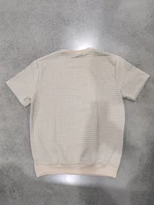 Vista dettagliata del retro di una t-shirt da uomo beige con trama trapuntata a quadri