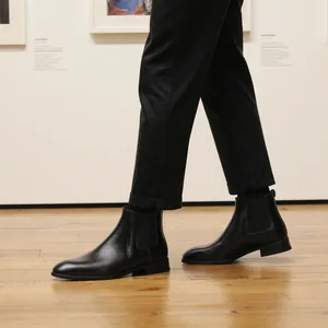 Vista laterale di stivali Chelsea classici in pelle nera da uomo in una galleria d'arte.