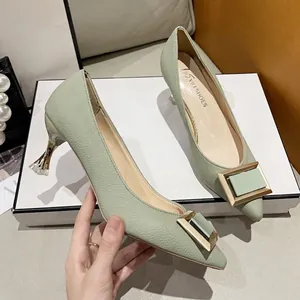 Tacones de aguja de punta verde claro con hebilla cuadrada dorada y acabado en cuero granulado.