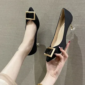 Elegantes tacones negros de punta con hebilla dorada cuadrada y tacón de diseño felino.