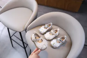 Detalle de zapatos de princesa para bebé con lazo de encaje, perlas y cuero texturizado