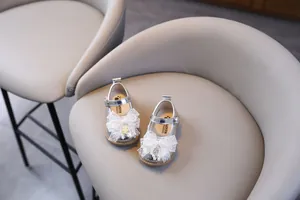 Vista detallada de zapatos plateados de princesa para bebé con lazos de encaje elegantes.