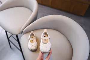Primer plano de zapatos blancos de princesa para bebé con detalles de lazos de encaje de perlas