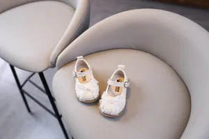 Detalle de zapatos blancos de princesa para niñas con lazo de encaje y perlas elegantes