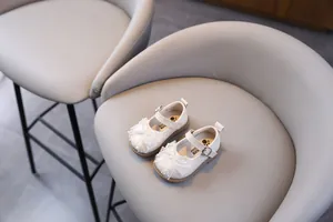 Detalle de zapatos de princesa blancos para niñas pequeñas con lazo de encaje y perlas