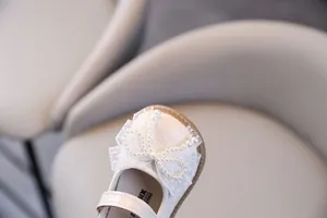 Primer plano de zapatos Mary Jane para bebé con un elegante lazo de encaje y perlas.
