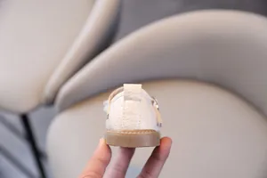 Detalle de zapatos blancos para bebé niña con suela blanda marrón y acabado texturizado.