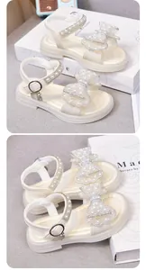Detaillierte Nahaufnahme eleganter weißer Mädchensandalen mit einer Perlen-Schleifen-Deko.