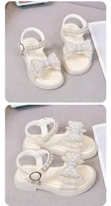 Makroansicht weißer Kindersandalen mit Details zur Perlen-Schleife und zum Riemchenverschluss.