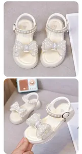 Nahaufnahme von weißen Prinzessinnen-Sandalen für Mädchen mit Strass- und Perlenbogen.