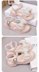 Detailansicht rosa Mädchensandalen mit perlenbesetzter Schleife und Herzriemen-Detail.