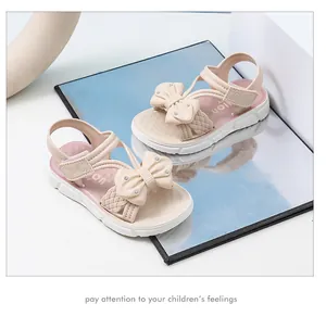 Primer plano de sandalias rosas para niña con lazo lindo y brillantes strass
