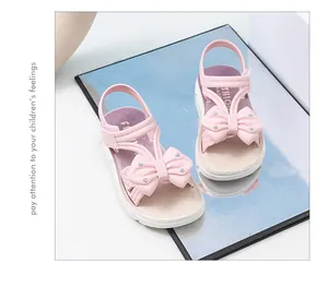 Primer plano de sandalias rosas para niñas con lazos decorativos y suelas blandas