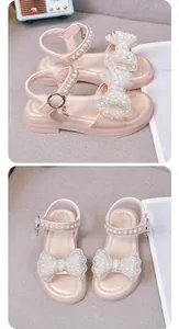 Detailansicht von rosa Mädchensandalen mit Perlen-Schleifen und verzierten Riemen.