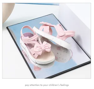 Vista detallada de sandalias rosas para niña con lazos elegantes y diamantes de imitación