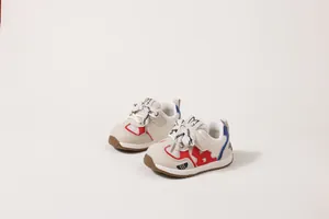 Dettaglio di sneaker traspiranti per neonati con accenti rossi e blu e suola morbida.