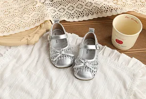 Detalle de elegantes sandalias plateadas tejidas con un bonito lazo para niñas pequeñas