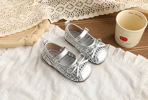 Primer plano de zapatos Mary Jane trenzados plateados para niñas con detalle de lazo