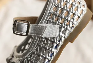 Primer plano del intrincado tejido plateado de estas sandalias caladas para niñas