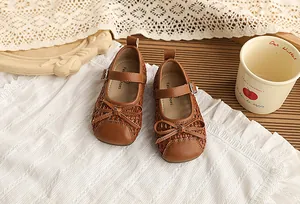 Primer plano de zapatos Mary Jane marrones trenzados y calados para niña con un lazo