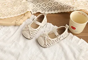 Vista detallada de las sandalias trenzadas crema para niñas con lazo y hebilla lateral.