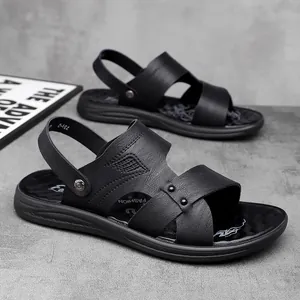 Detailansicht schwarzer Herren-Ledersandalen mit rutschfester Sohle auf grauem Grund.