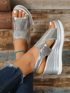 Stylish silver metallic peep-toe wedge sandals with thick platform soles on model