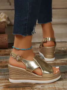 Detailed close-up of gold metallic wedge platform sandals with buckle strap and peep toe.