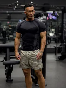 Close-up detail of a male athlete wearing a black compression tee and camo shorts