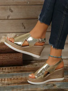 Detailed macro view of stylish metallic gold wedge sandals with peep-toe and buckle