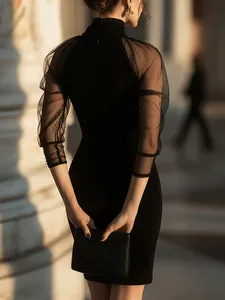 Elegante vestido ajustado negro con mangas de malla transparente y cuello alto chic