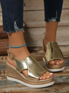 Close-up of gold metallic platform wedge sandals with buckle strap and open toe design.