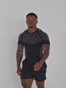 Athletic male model wearing a black compression t-shirt and gym shorts in a studio