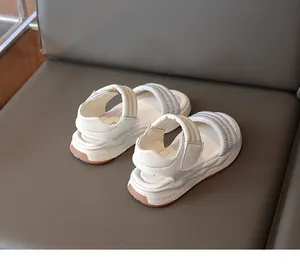 Detailansicht der weißen Mädchensandalen mit glitzernden Strassriemen und dicken Sohlen