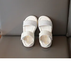 Detailansicht weißer Mädchensandalen mit glitzernden Strassriemen von oben