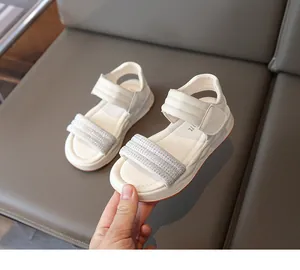 Detailaufnahme von weißen Sandalen für Mädchen mit funkelnden Strassriemen und Verschluss