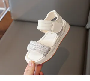 Nahaufnahme der stilvollen cremeweißen Mädchensandalen mit glitzernden Strassriemen
