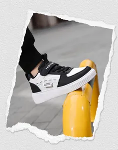Side view of children's black and white casual board shoes with velcro strap.