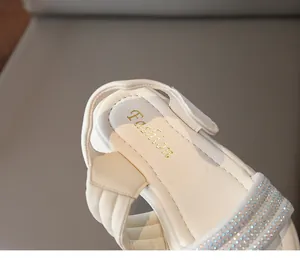 Detailansicht von cremefarbenen Mädchensandalen mit Strassriemen und Klettverschluss