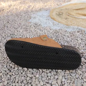 Detailed view of the black anti-slip wavy textured sole of these casual brown clogs.
