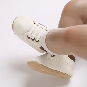 Detailed view of white PU leather baby walking shoes with soft non-slip soles on feet